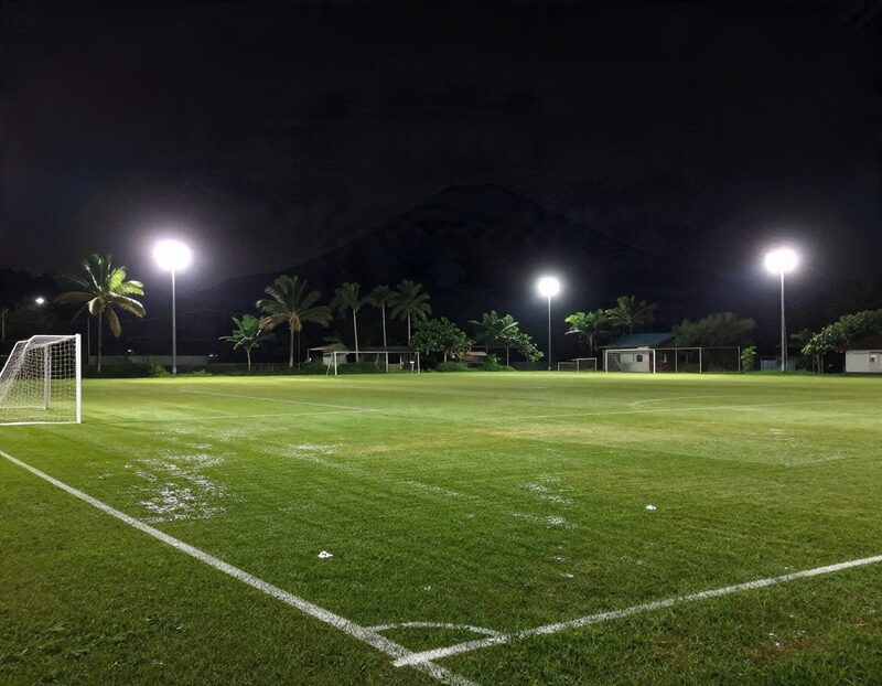 Terrain de football éclairé la nuit sous les tropiques avec un volcan en silhouette